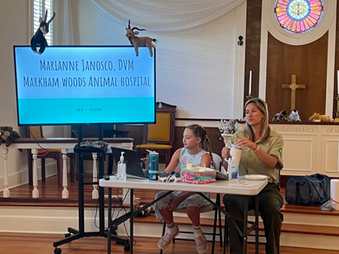 A veterinarian and her daughter sitting at a table giving a presentation.