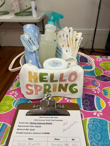 A rope basket with homemade cleaning supplies including unpaper towels and a towel that says hello spring