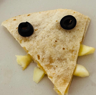 A triangle of quesadilla made to look like a crocodile face