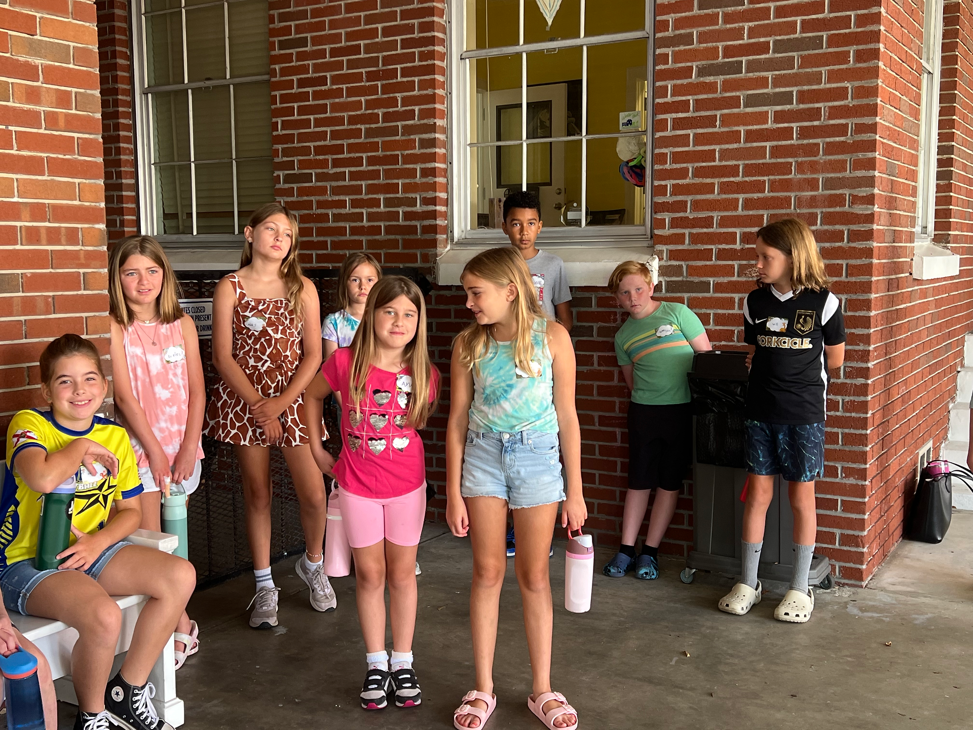 A group of children standing in front of a brick wall