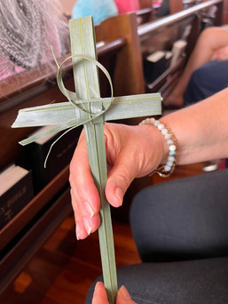 palm leaf folded into a cross, held by a hand