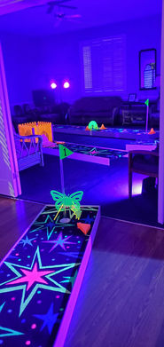 a glow in the dark mini golf course set up under a black light set up inside fellowship hall