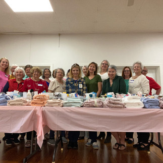 a group of women standing behind a table holding toiletry items