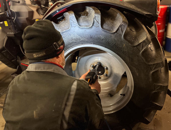 Mann der Kfz-Landtechnik Norbert Zöchbauer schraubt Traktorreifen an