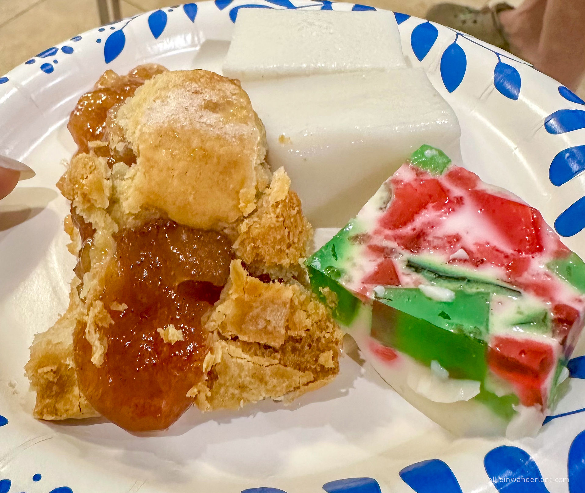 A plate of Hawaiian holiday desserts featuring a flaky and golden homemade peach cobbler, a slice of smooth haupia (Hawaiian coconut pudding), and a festive red and green stained glass Jell-O dessert with sweetened condensed milk. The colorful assortment is served on a disposable plate, capturing the flavors of a special island celebration.