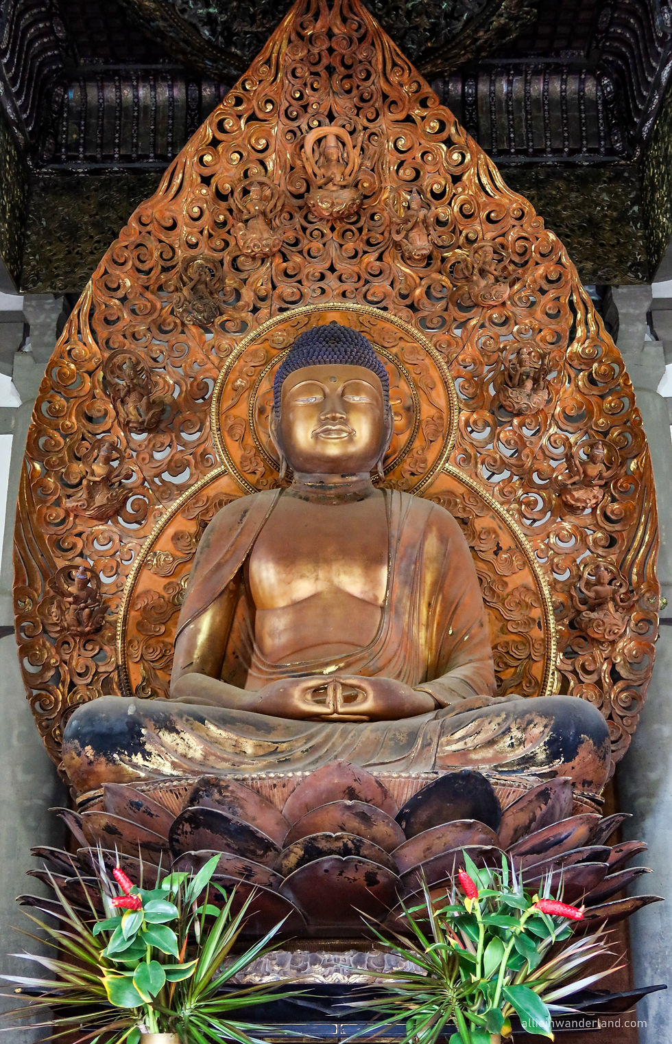 Golden Amida Buddha statue inside the Byodo-In Temple in Kāneʻohe, O‘ahu, Hawaii, surrounded by intricate lotus carvings and floral offerings, representing peace and enlightenment.