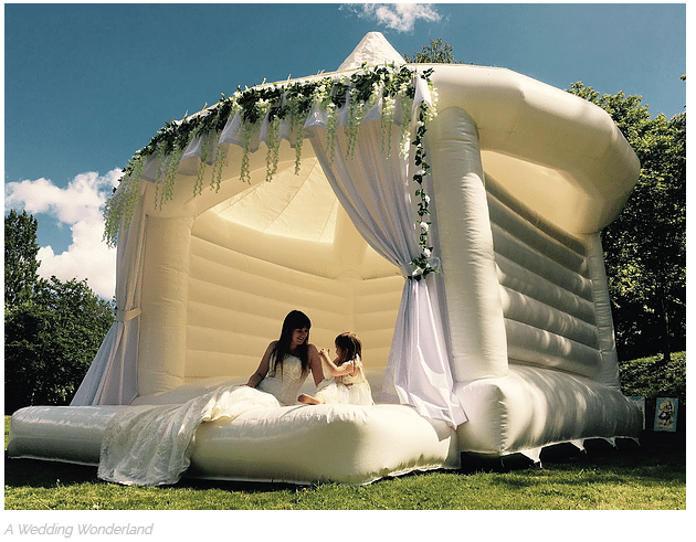 Bride and flower girl in white wedding bounce house