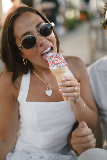 a woman wearing sunglasses is eating an ice cream cone with sprinkles