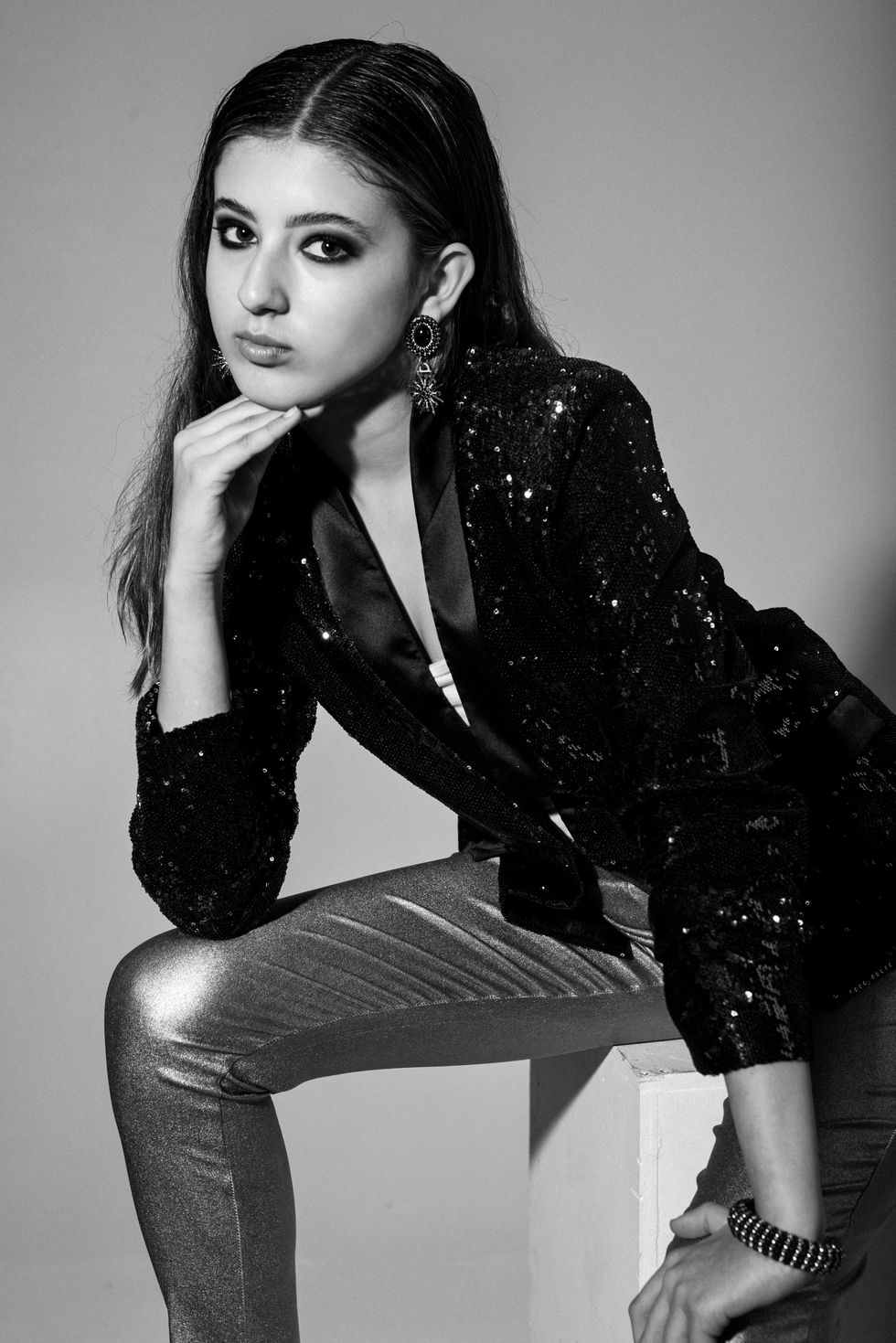 Black and white editorial portrait in a sequinned black jacket, leaning forward with chin on hand, in Melbourne, Australia, styling by Tamarra McNaught, founder of TITO STYLE