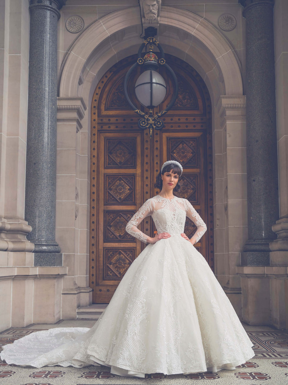 Bride in a Jullia Bridal long-sleeve lace ballgown before the grand carved doors of Parliament House, Melbourne; creative direction and styling by Tamarra McNaught, founder of TITO STYLE.