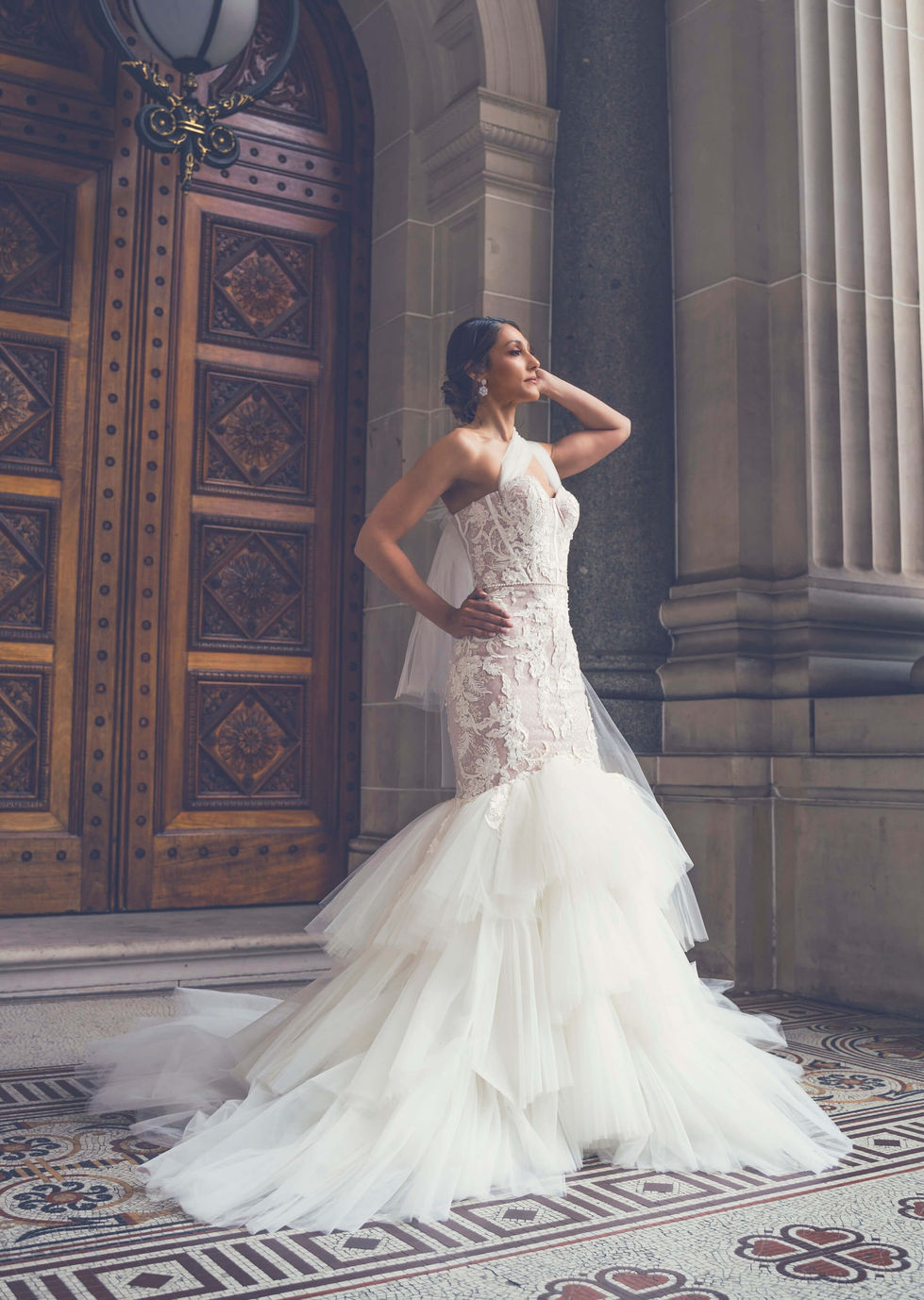Bride in a Jullia Bridal halterneck lace mermaid gown with a tiered tulle skirt at the carved doorway of Parliament House, Melbourne; creative direction and styling by Tamarra McNaught, founder of TITO STYLE.