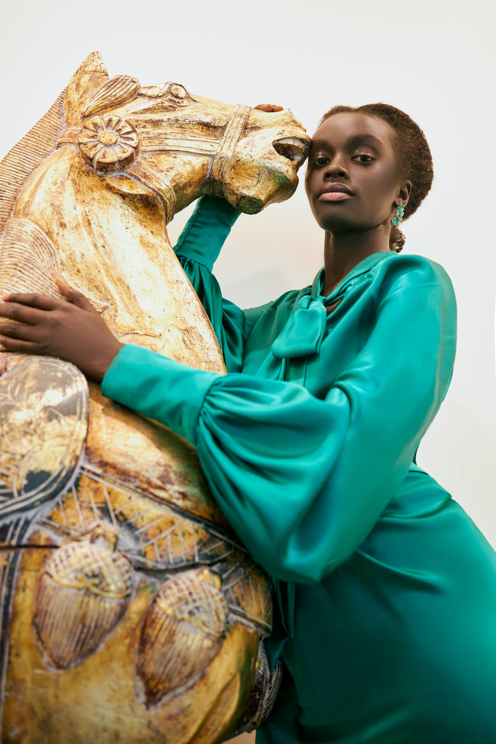 An emerald green satin gown posed beside a gilded horse sculpture. A Tanya Didenko Couture gown, with creative direction and styling by Tamarra McNaught, founder of TITO STYLE, at Riverlea Estate, Warrandyte, Victoria, Australia.