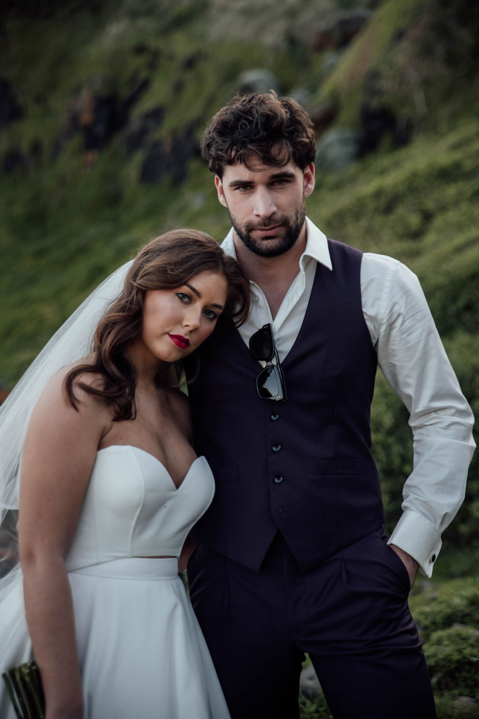 A couple close, the bride strapless, the groom in a dark waistcoat. A gown by The Sposa Group with menswear by YSG Tailors, styling by Tamarra McNaught, founder of TITO STYLE, at Cairn Beach, Australia.