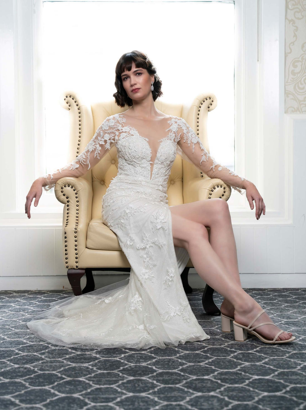 Bride in a sheer-sleeve Jullia Bridal lace gown seated in a leather wingback chair at The Hotel Windsor, Melbourne; creative direction and styling by Tamarra McNaught, founder of TITO STYLE.