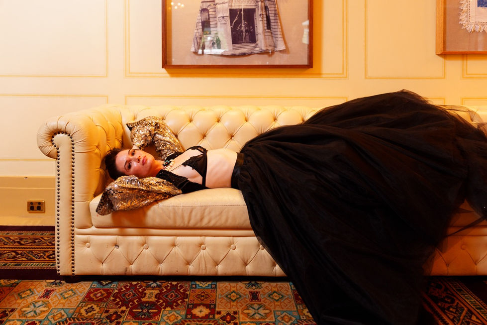 Model reclining in couture on a chesterfield sofa, editorial styling by Tamarra McNaught of TITO STYLE, The Windsor Hotel, Melbourne.