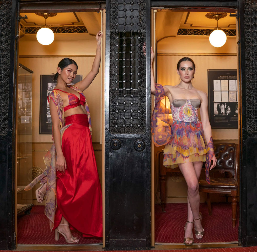 Two models in In Aetheria, one in a red gown and one in a marbled corset minidress, framed in ornate black heritage doorways at The Hotel Windsor, Melbourne, Australia; creative direction and styling by Tamarra McNaught, founder of TITO STYLE.