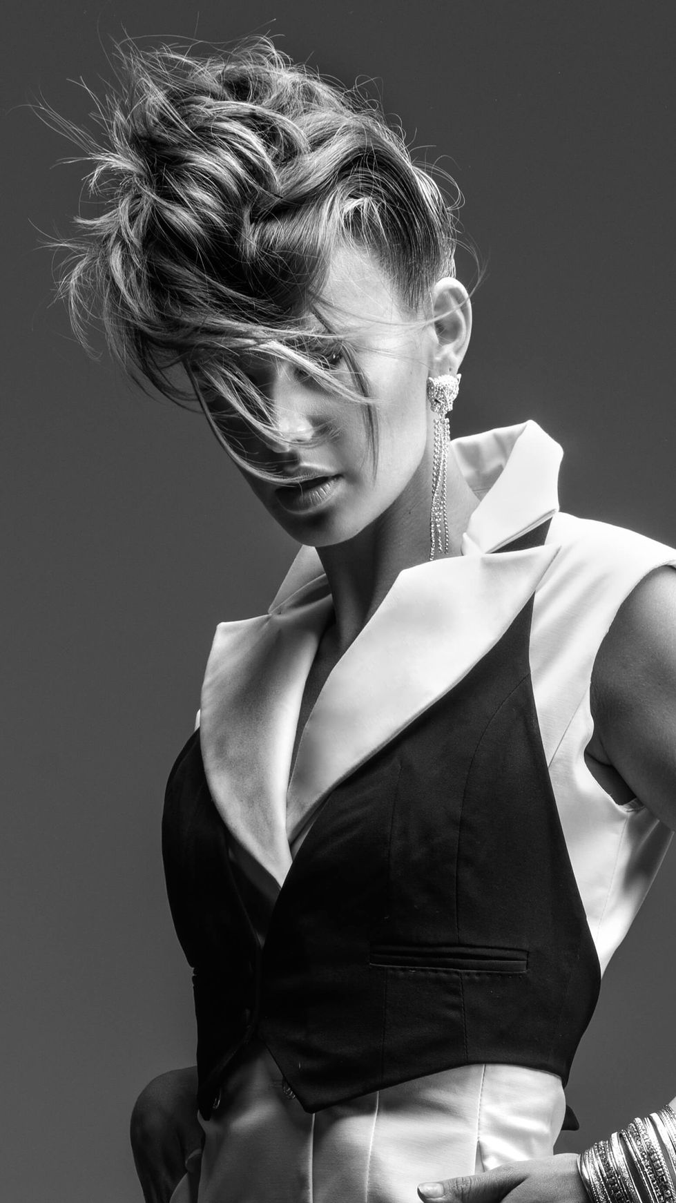 Model with an updo in a black and white tuxedo waistcoat by Moss & Spy with crystal earrings, hair by Tracey Hughes, styled by TITO STYLE.