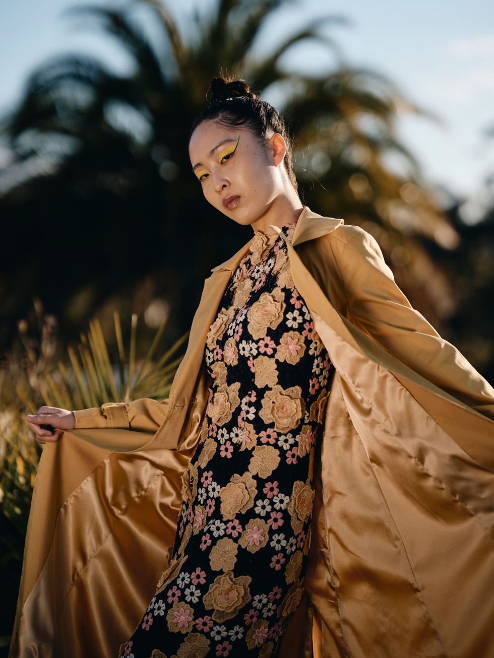 A tan trench-style coat worn over a printed dress in the vineyard. A Moss & Spy look, with creative direction and styling by Tamarra McNaught, founder of TITO STYLE, at Riverlea Estate, Warrandyte, Victoria, Australia.