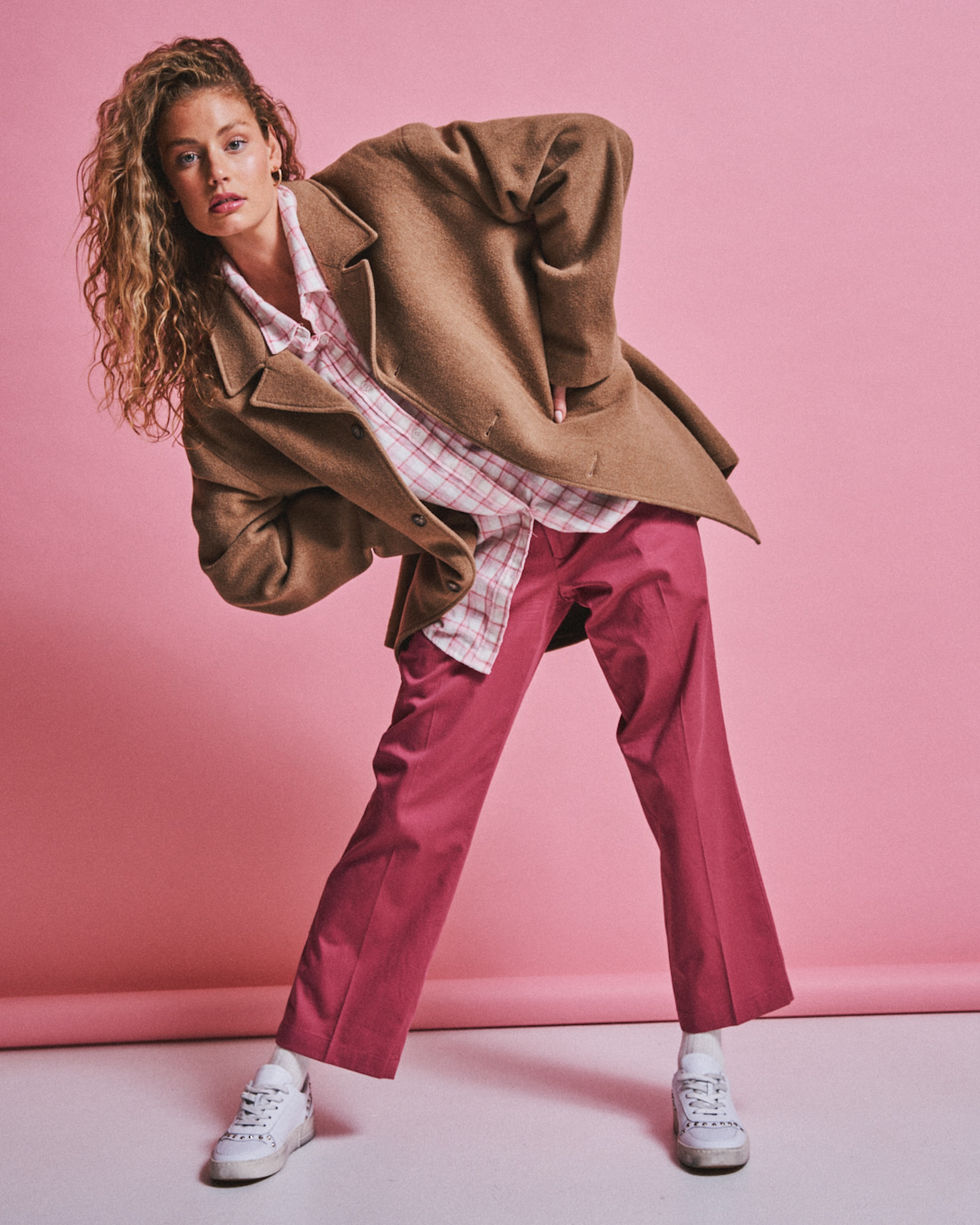 Model in a tan blazer and red trousers posing against a pink studio backdrop, Melbourne, Australia; styling by Tamarra McNaught, founder of TITO STYLE.