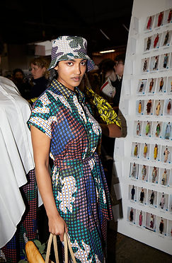 A model styled by Tamarra McNaught wears a bold printed dress and matching bucket hat backstage at Melbourne Fashion Week (M/FW), holding a baguette-filled tote. As the fashion and celebrity stylist behind TITO STYLE, Tamarra’s styling injects playful sophistication into the runway lineup in Melbourne, Australia.