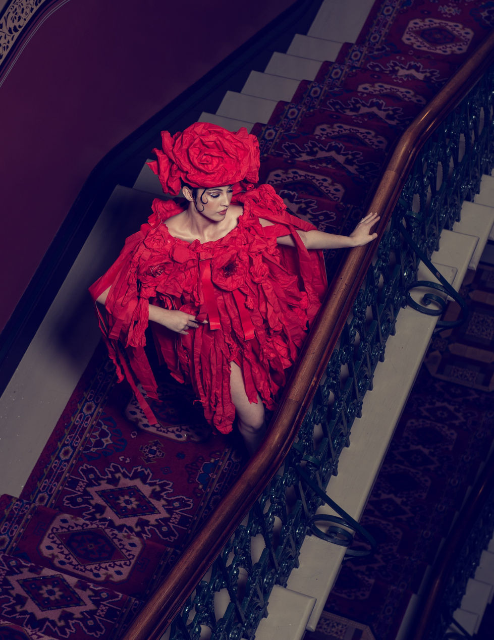 Overhead view of a red paper rose gown by Curl Paper on the heritage staircase of The Hotel Windsor, styled by TITO STYLE.