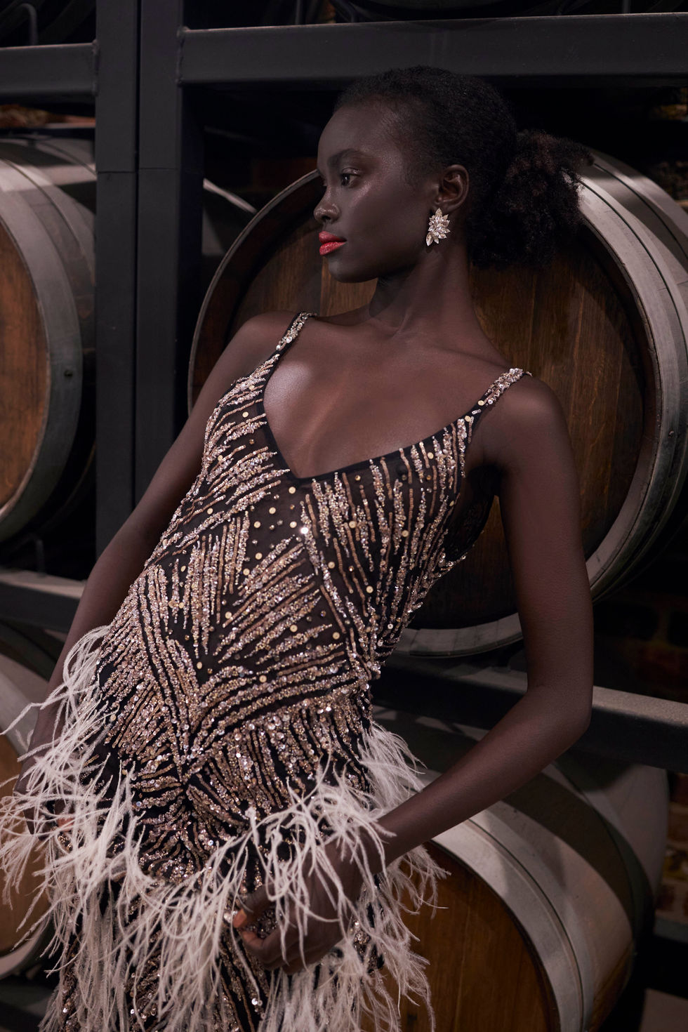 A navy feathered one-shoulder gown in the estate cellar, shot in profile among the wine barrels. A Moss & Spy gown, with creative direction and styling by Tamarra McNaught, founder of TITO STYLE, at Riverlea Estate, Warrandyte, Victoria, Australia.
