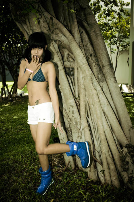 Leaning against a banyan tree in blue Rubber Duck boots and a teal bikini top, creative direction and styling by Tamarra McNaught, founder of TITO STYLE, for Rubber Duck in Koh Samui, Thailand.
