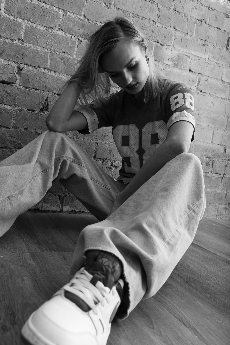 Model seated against a brick wall in a striped knit, direct gaze, editorial styling by TITO STYLE fashion stylist Tamarra McNaught, Melbourne.