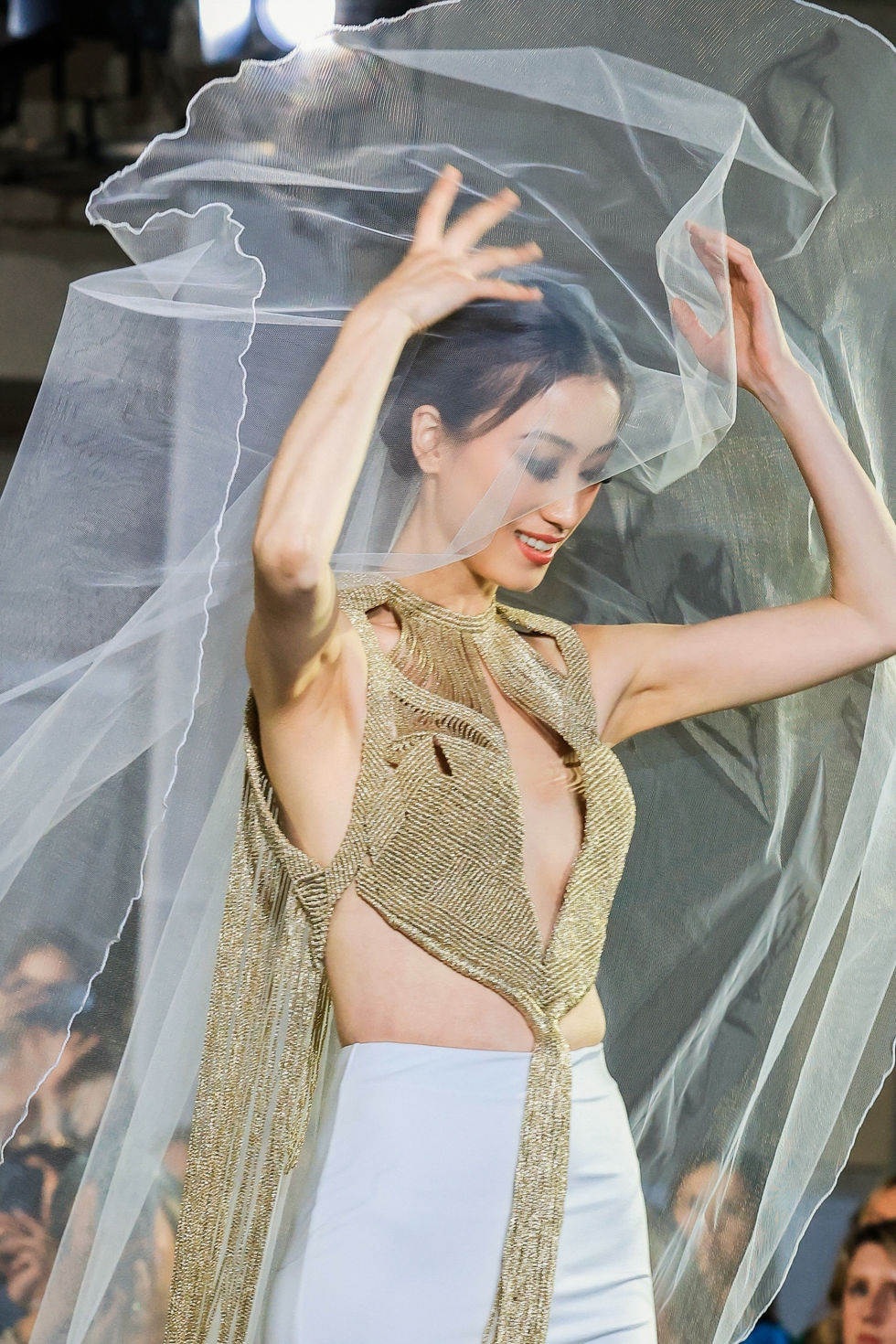 A gold and nude two-piece with a sheer veil, arms raised. A Corde Couture look, with creative direction and styling by Tamarra McNaught, founder of TITO STYLE, at The Hotel Windsor, Melbourne, Australia.