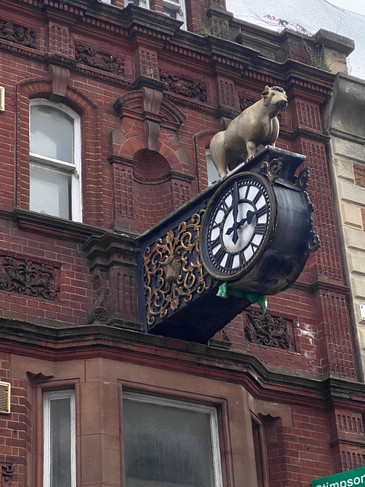 A black clock with a white dial jutting out into the High Street. On top of it is a small golden bull.