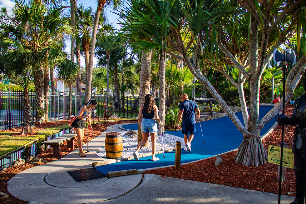 Guests enjoying a daytime round on the blue putting greens among Castle Golf’s palms.