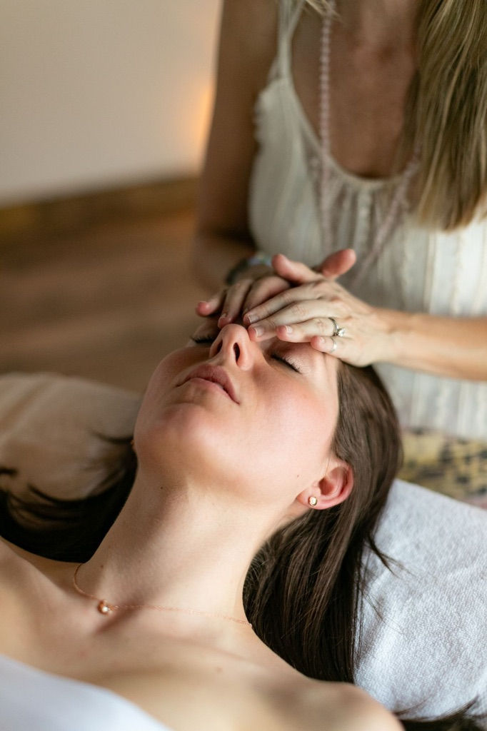 A woman receives the benefits of reiki from a healer.