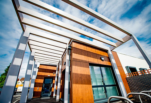 Foleshill-HC-entrance-with-wood-effect-panelling-black-frame-windows-metal-canopy-cream-re