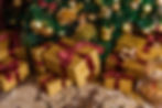 Gold-wrapped gifts with red bows sit under a decorated Christmas tree with gold ornaments. A festive carpet sets a cozy holiday mood.
