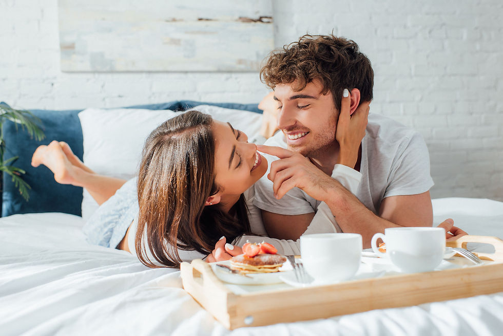 Selective focus of young couple touching each other near breakfast tray on bed
