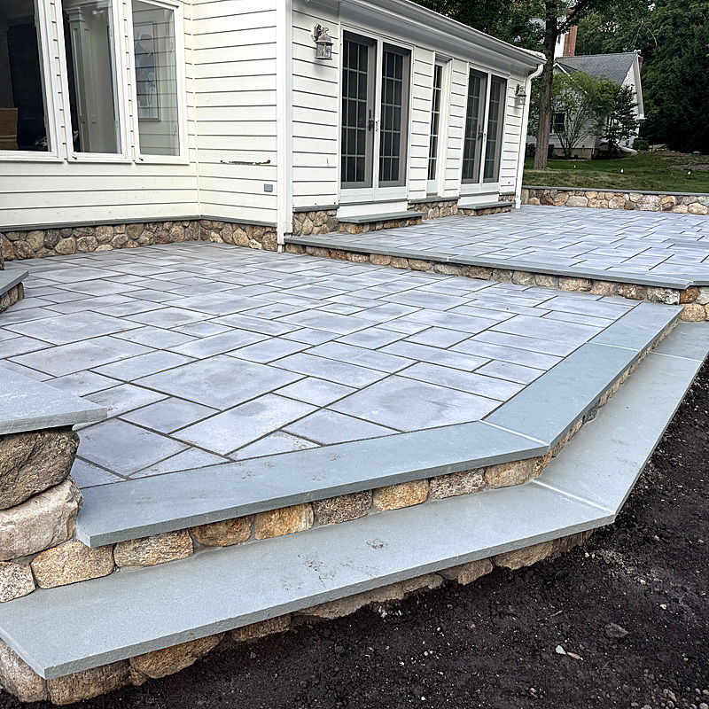 Modern grey stone patio with multi-level steps and siding.
