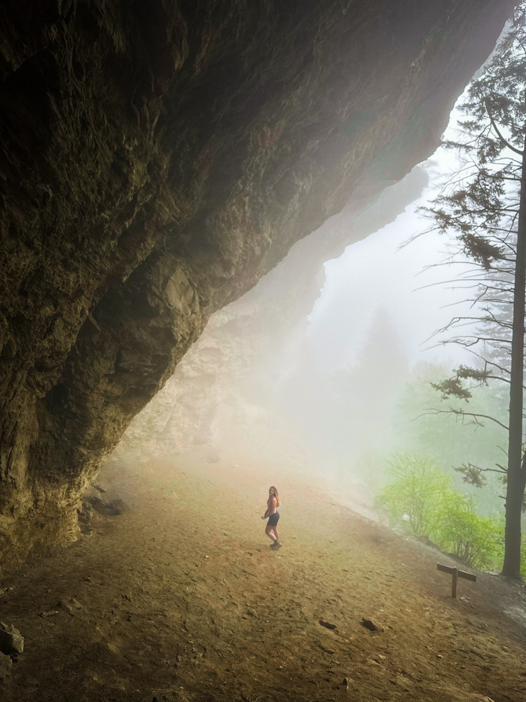 A girl stands under a cavelike formation
