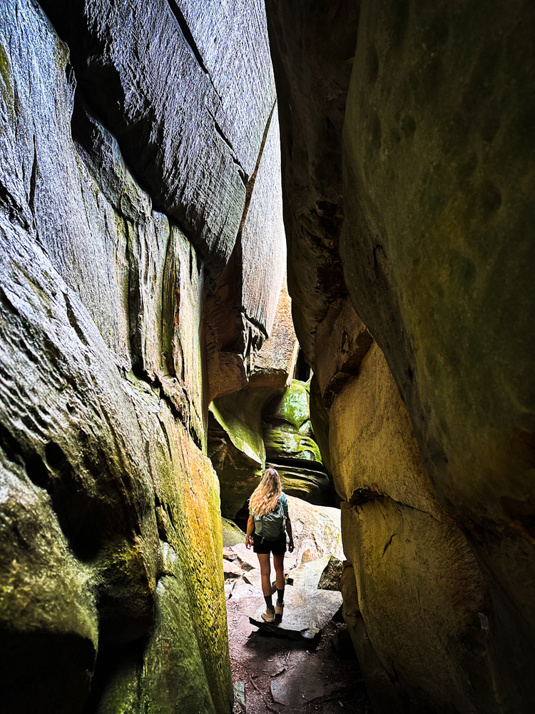 A girl walks through large sandstone rock formations