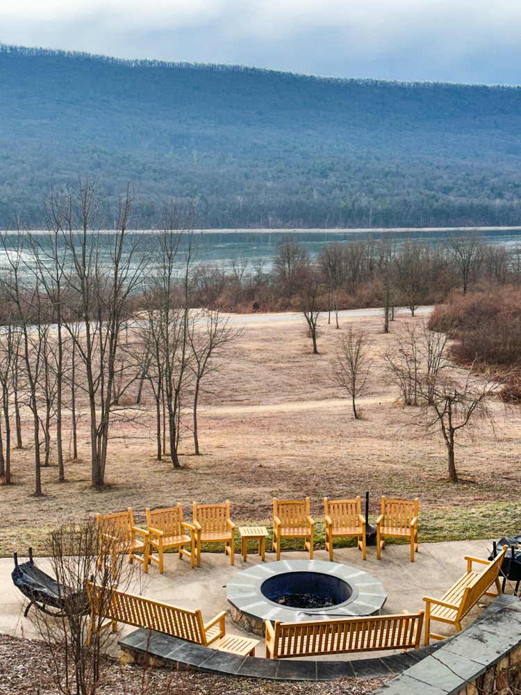 A fire pit and chairs by a lake
