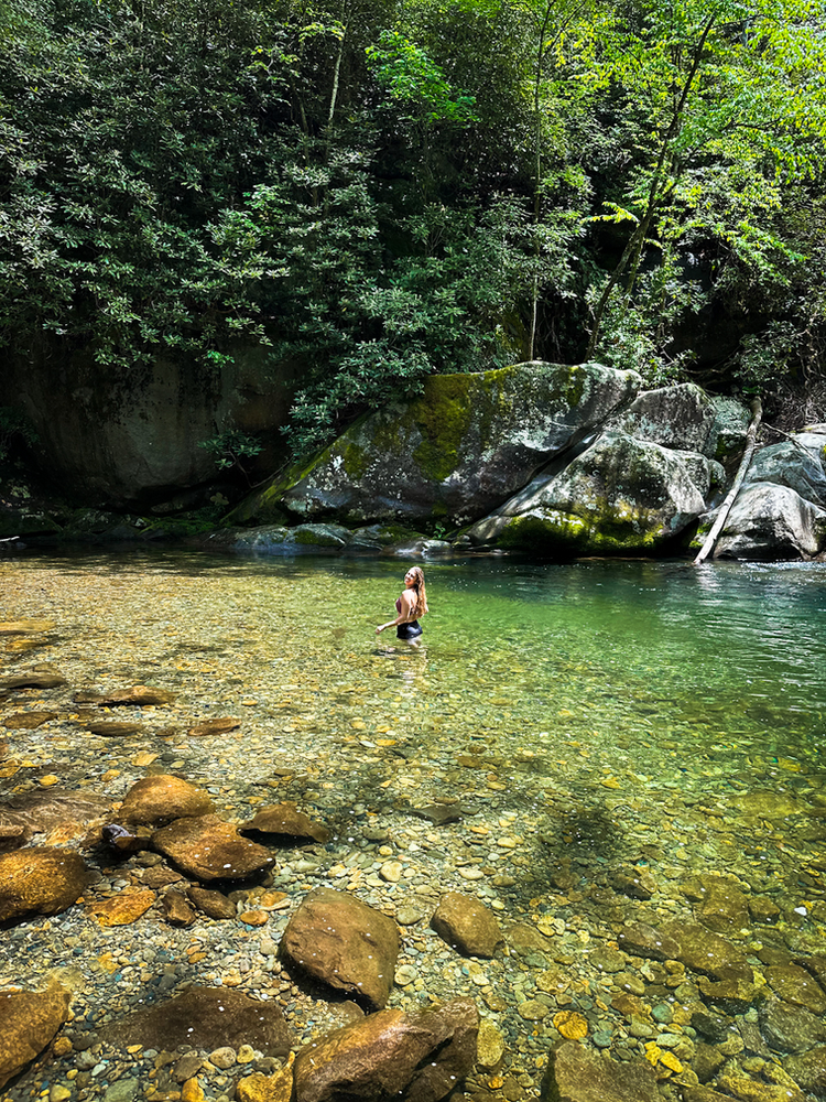 A girl standing in a natural swimming hole 