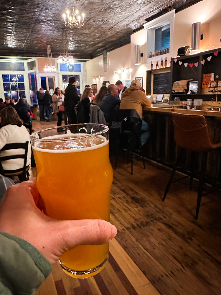 A beer held out in front of a person in a brewery