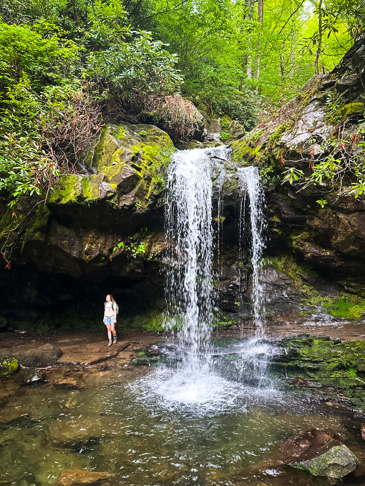 A girl standing next to a waterfall 