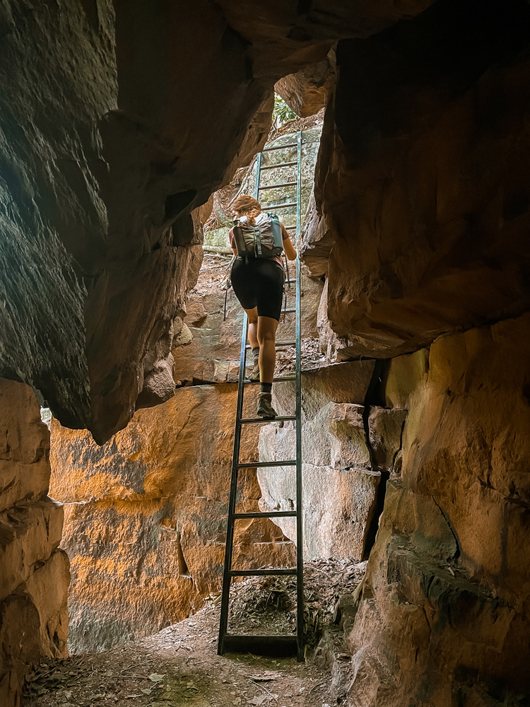 A girl descends a ladder through a cliff 
