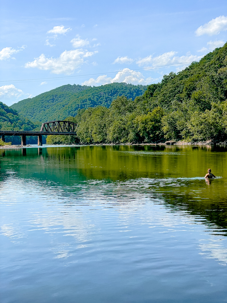 Swimming in the river with a bridge and mountains in the background