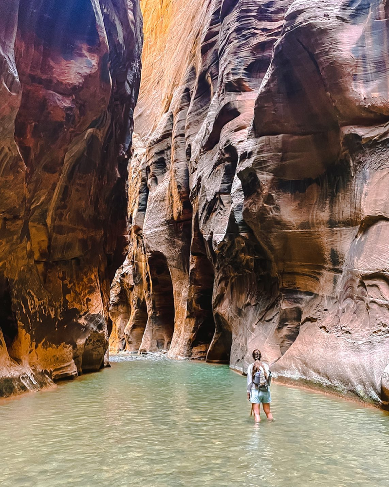 A woman is standing in the river in a narrow portion of the canyon called "Wall Street" 
