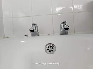 Close-up of a bathtub faucet setup with two chrome taps and a circular drain