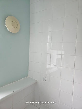 A light blue wall corner with a circular ceiling fixture and a white tiled wall
