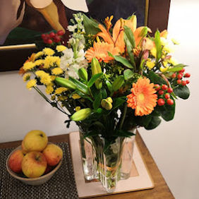 A vibrant bouquet of orange, yellow, and white flowers in a clear vase
