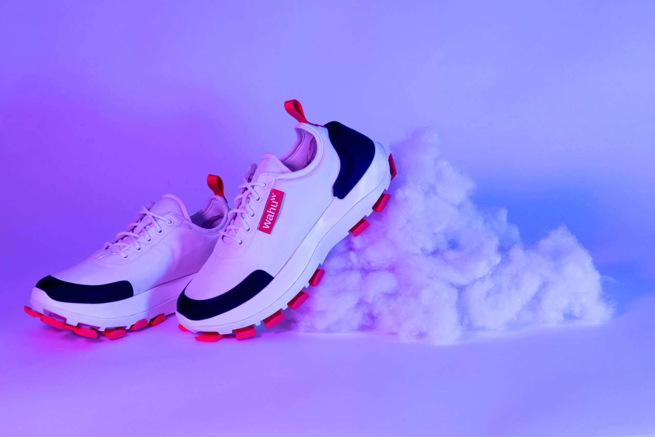 White, black and orange shoes resting on clouds and with a purple background