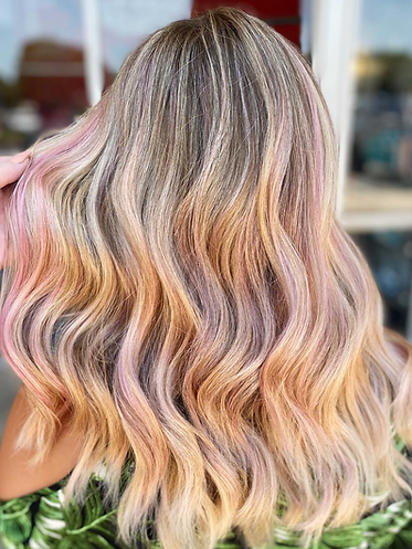 A young female woman with blonde waves with subtle pink highlights